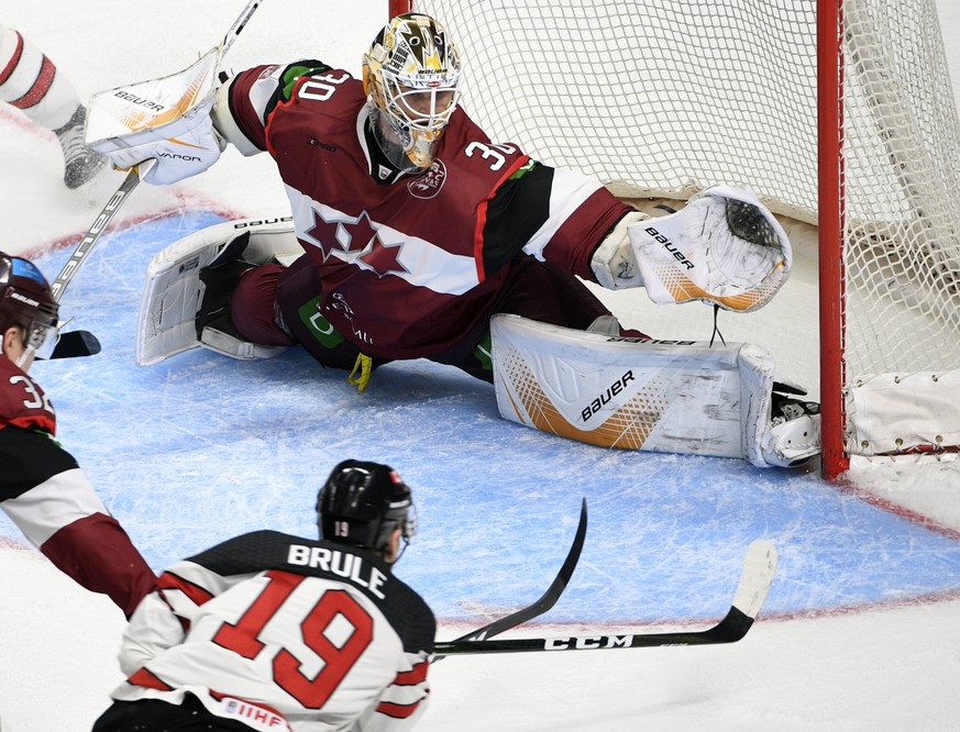 Latvia's goalie Elvis Merzlikins and Canada's Gilbert Brule fight for the puck during an exhibition hockey game in Riga, Latvia, Sunday, Feb. 4, 2018. (AP Photo/Roman Koksarov)