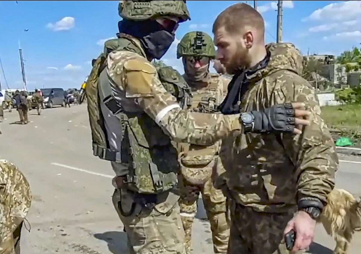 epa09963857 A still image taken from handout video made available on 21 May 2022 by the Russian Defence Ministry's press service shows Russian servicemen frisk the acting commander of the Ukraini ...
