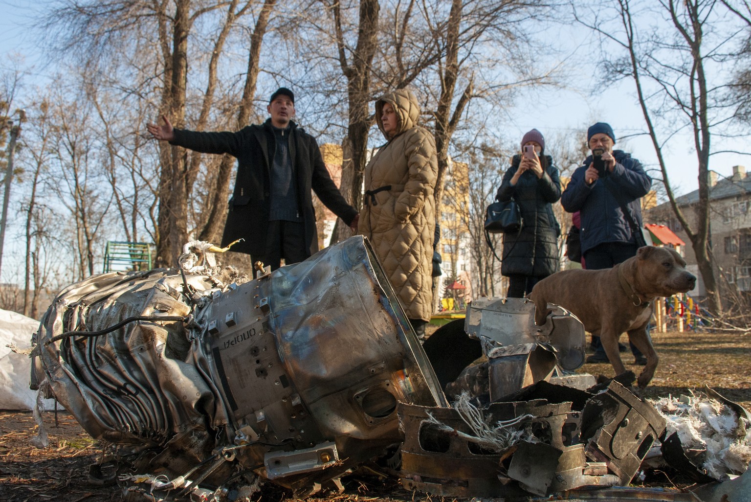 People stand next to fragments of military equipment on the street in the aftermath of an apparent Russian strike in Kharkiv in Kharkiv, Ukraine, Thursday, Feb. 24, 2022. Russian troops have launched ...