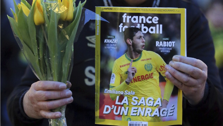 A FC Nantes soccer fan displays an old copy of French soccer magazine, France Football, featuring FC Nantes soccer player Emiliano Sala of Argentina, during a tribute in Nantes, western France, Tuesda ...