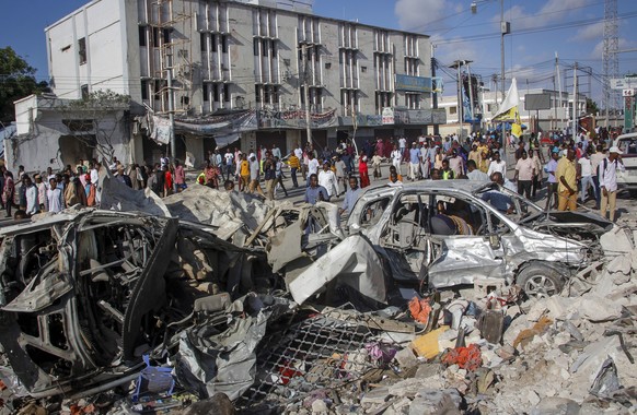 People walk amidst destruction at the scene, a day after a double car bomb attack at a busy junction in Mogadishu, Somalia Sunday, Oct. 30, 2022. Somalia&#039;s president says multiple people were kil ...