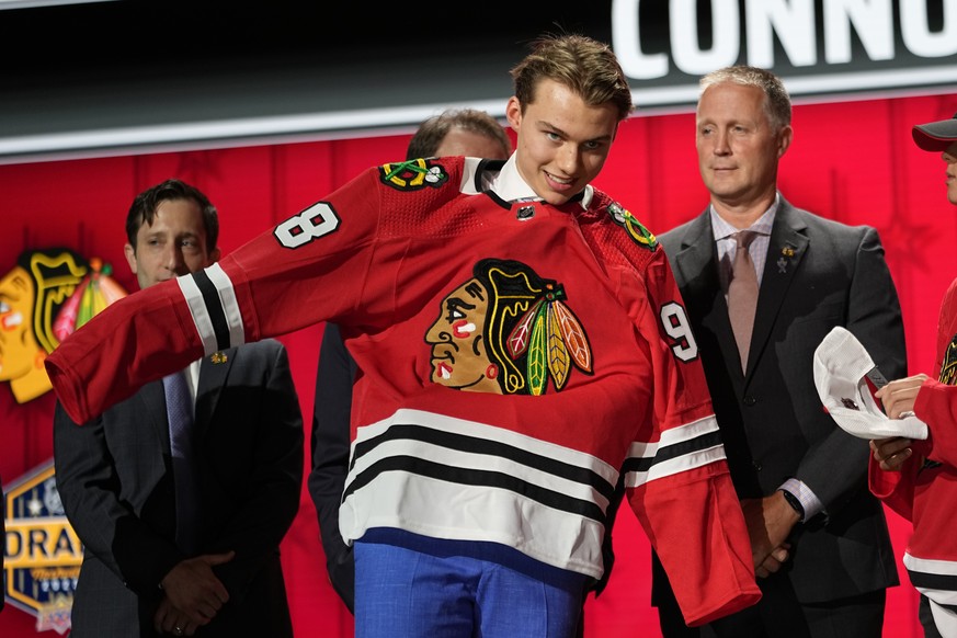 Chicago Blackhawks first round draft pick Connor Bedard puts on his jersey after being picked by the team during the first round of the NHL hockey draft, Wednesday, June 28, 2023, in Nashville, Tenn.  ...