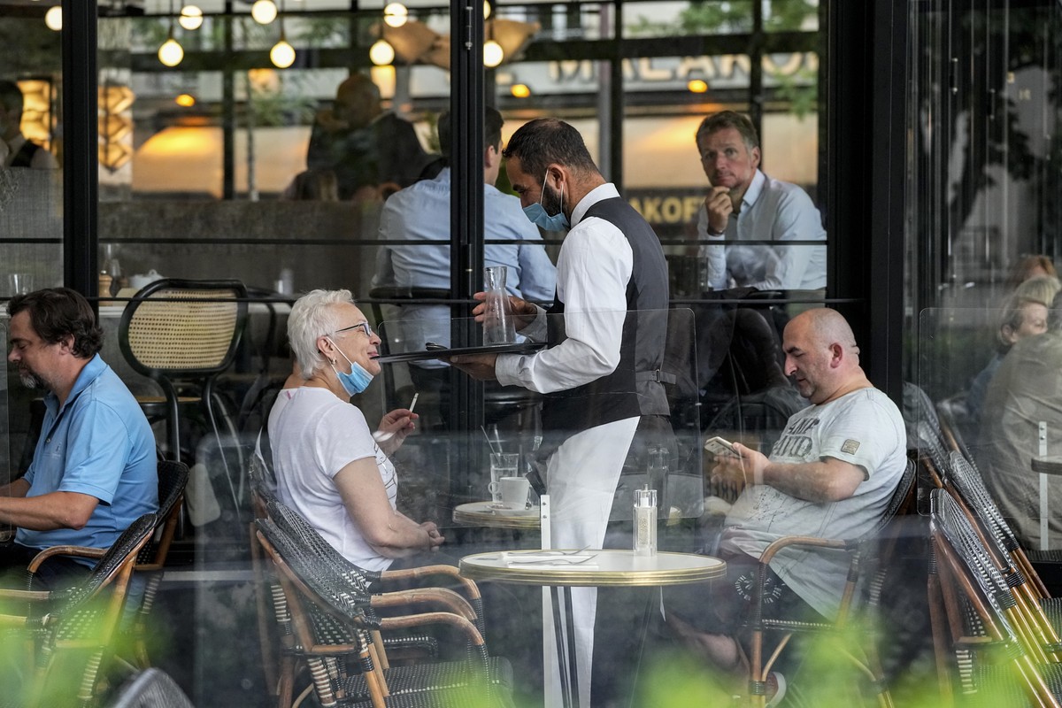 A waiter wearing a face mask to protect against coronavirus serves at a restaurant terrace in Paris, Monday, July 26, 2021. France's parliament approved a law requiring special virus passes for a ...