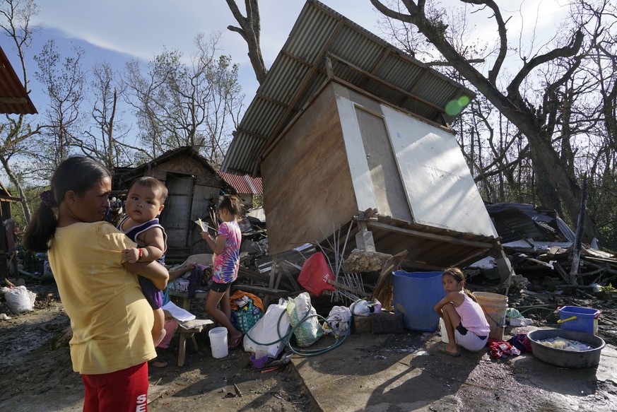 Residents stand amid damaged homes following Typhoon Rai in Talisay, Cebu province, central Philippines on Saturday, Dec. 18, 2021. The strong typhoon engulfed villages in floods that trapped resident ...