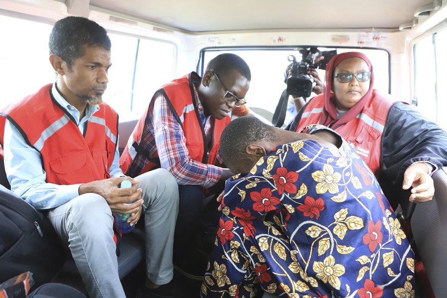 A woman, one of the followers of a Christian Cult that has killed dozens bends as she sits next to Kenya Red Cross officials inside a car after being rescued by police in a forest in Shakahola, outski ...