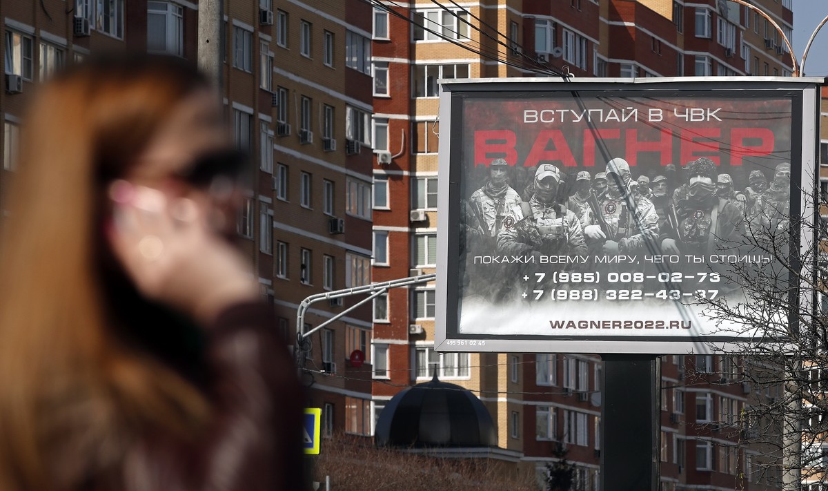 epa10569583 A woman walks in front of an advertising billboard reading 'Join the PMC Wagner' promoting the Wagner Group military company in a residential area in Moscow, Russia, 12 April 202 ...