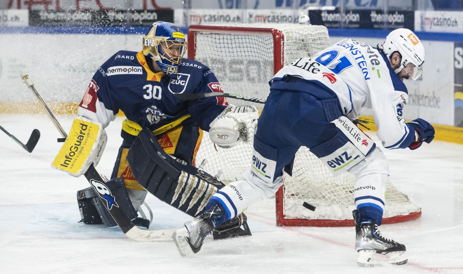 Zugs Torhueter Leonardo Genoni, links, kaempft um den Puck gegen Zuerichs Denis Hollenstein, rechts, im fuenften Playoff-Final Eishockeyspiel der National League zwischen dem EV Zug und ZSC Lions am M ...