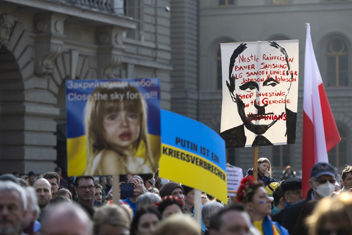 epa09836282 A protester holds a placard reading 'Nestle, Raiffeisen, Bayer, Samsung, LG, Sanofi, Unilever, Johnson &amp; Johnson - Stop investing in the genocide of Ukrainians' during a demo ...
