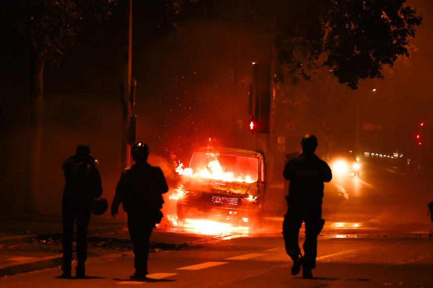 epaselect epa10720120 People walk next to a car burned during clashes between protesters and riot police in Nanterre, near Paris, France, 30 June 2023. Violence broke out all over France after police  ...