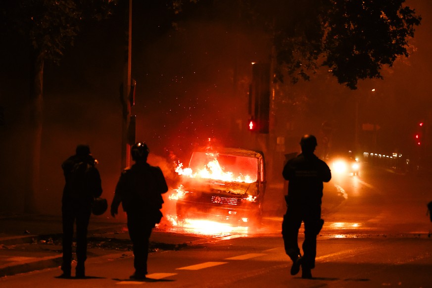 epaselect epa10720120 People walk next to a car that burned out during clashes between protesters and riot police in Nanterre, near Paris, France, June 30, 2023. Violence broke out across France after police...