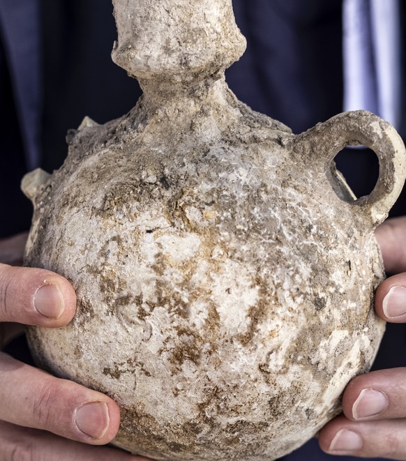 An Israel Antiquities Authority employe holds a jar from a massive ancient winemaking complex dating back some 1,500 years in Yavne, central, Israel, Monday, Oct. 11, 2021. Israeli archaeologists said ...