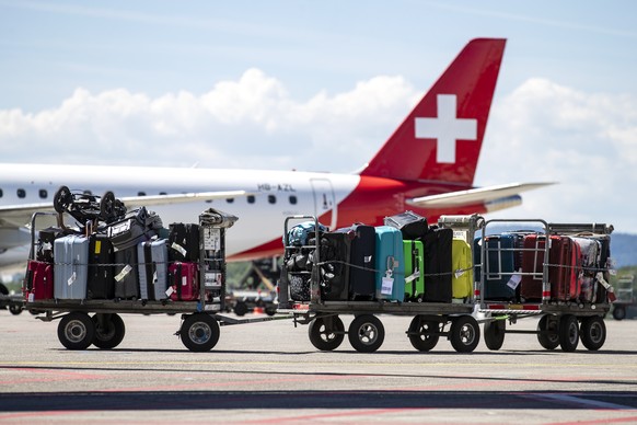 Koffer auf Gepaeckwagen stehen vor einem Helvetic Flugzeug am Flughafen Zuerich am Dienstag, 12. Juli 2022. (KEYSTONE/Alexandra Wey)