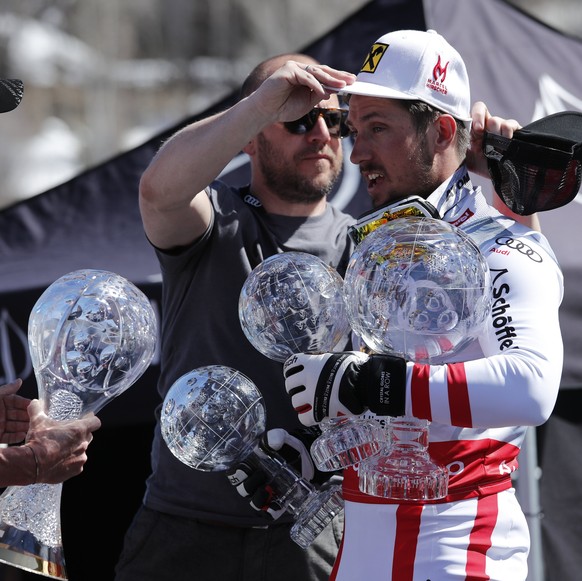 epa05858922 Marcel Hirscher of Austria (R) gets a hand carrying his 2017 Overall Crystal Globe and Globes in other events before a photo-op during the Audi FIS World Cup Finals in Aspen, Colorado, USA ...