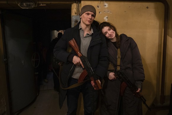 Newly married couple Yarina Arieva and Svyatoslav Fursinb, left, pose for photo after they joined the ranks of the city territorial defense the day after they got married in Kyiv, Ukraine, Friday, Feb ...