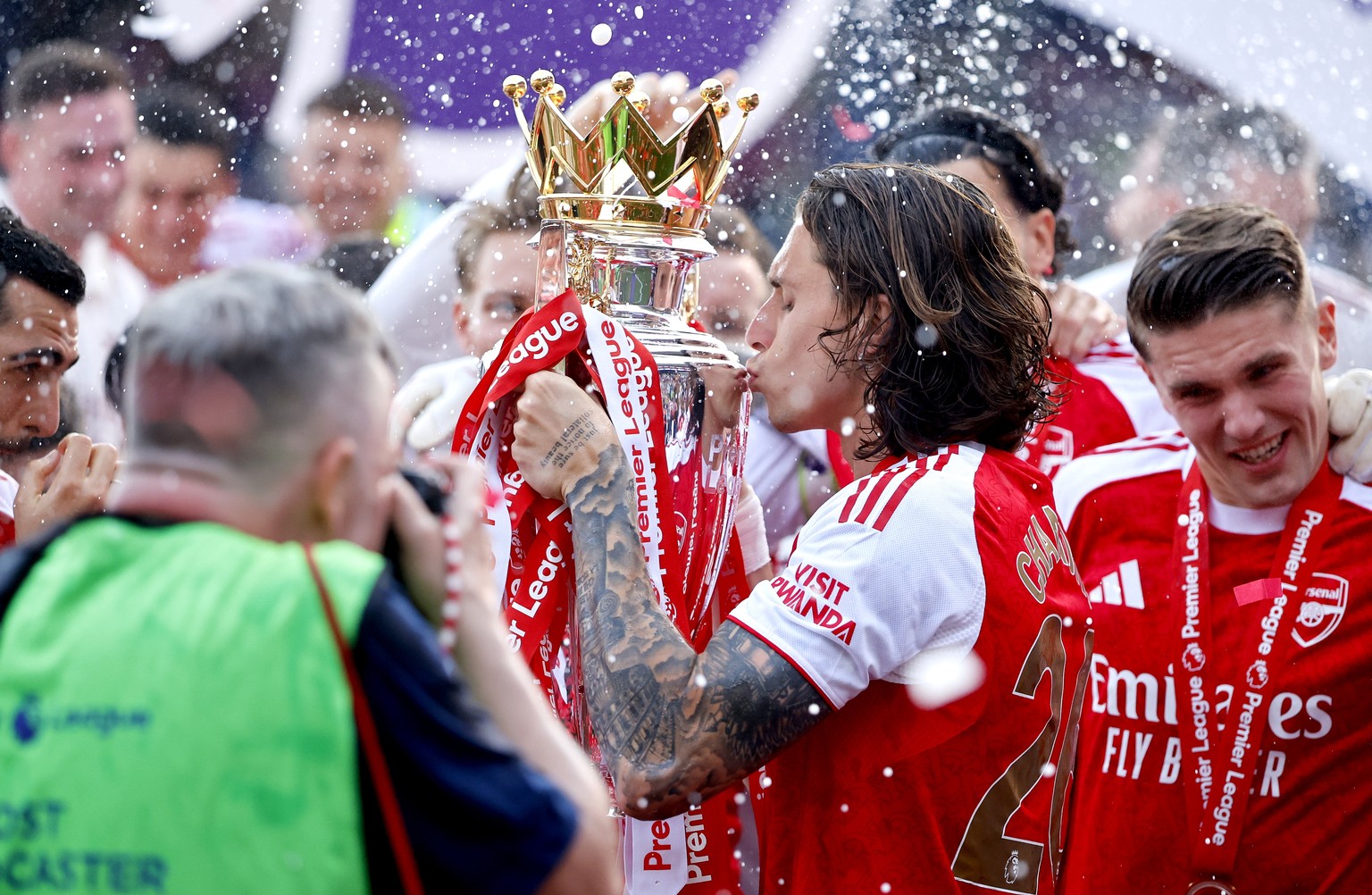 epa12991398 Arsenal player Riccardo Calafiori (C) kisses the Premier League trophy as he and teammates celebrate at the end of the English Premier League match Crystal Palace against Arsenal FC, in Lo ...