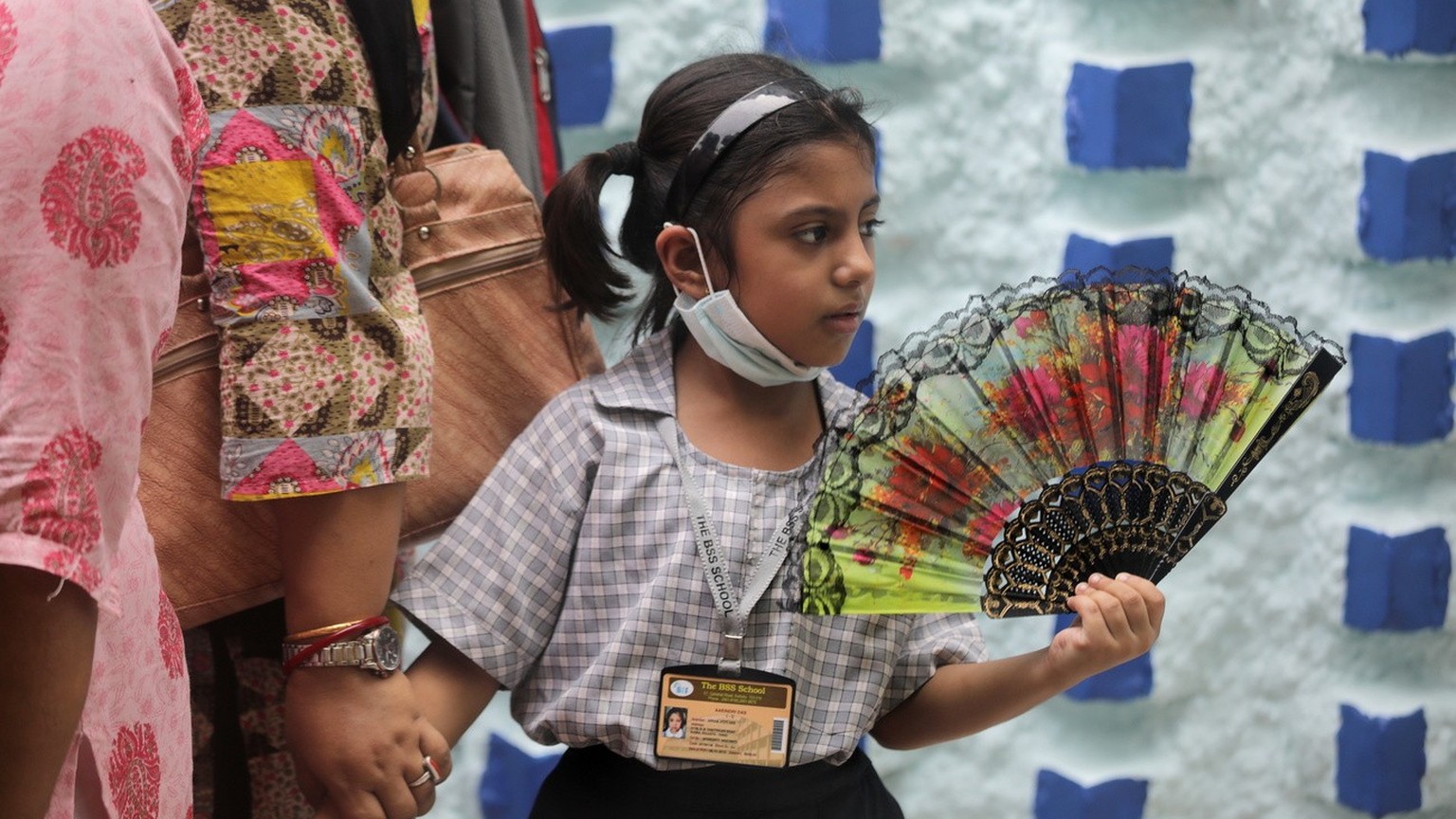 epa09913861 A young girl holds a hand fan as she waits outside a school during a hot day in Kolkata, India, 28 April 2022. The summer, or pre-monsoon season, occurs from March to July in eastern India ...