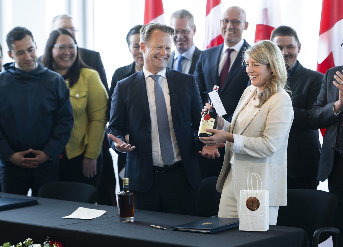 Danish Foreign Minister Jeppe Kofod, center, and Canada's Canadian Foreign Minister Mélanie Joly, right, trade gifts of liquor after the signing of an agreement that will establish a land border  ...