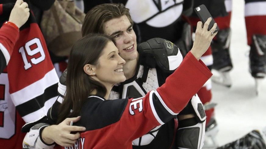 New Jersey Devils center Nico Hischier, right, of Switzerland, takes a photo with a fan after defeating the Toronto Maple Leafs in an NHL hockey game, Thursday, April 5, 2018, in Newark, N.J. (AP Phot ...