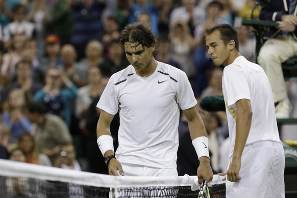 Rafael Nadal , left, of Spain walks to pickup the racket of Lukas Rosol of the Czech Republic after Rosol defeated Nadal in a second round men&#039;s singles match at the All England Lawn Tennis Champ ...