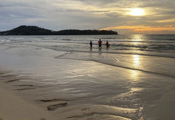 Tourists walk on Bang Tao Beach in Phuket, southern Thailand, Friday, Oct. 22, 2021. Thailand is accelerating plans to reopen the country to foreign tourists, slashing mandatory quarantines beginning  ...