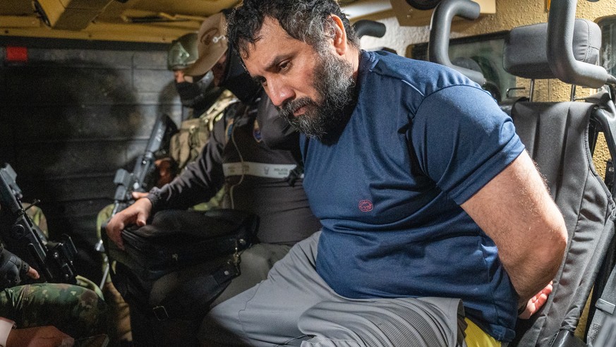 epa12198026 Drug trafficker Jose Adolfo Macias Villamar 'Fito' (R) is guarded as he is moved in Guayaquil, Ecuador, 25 June 2025. 'Fito' arrived at the Guayaquil Air Base after bei ...