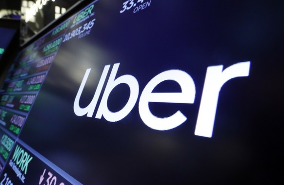 FILE - In this Aug. 16, 2019 file photo, the logo for Uber appears above a trading post on the floor of the New York Stock Exchange. Uber is formally recognizing a major British trade union so it can  ...