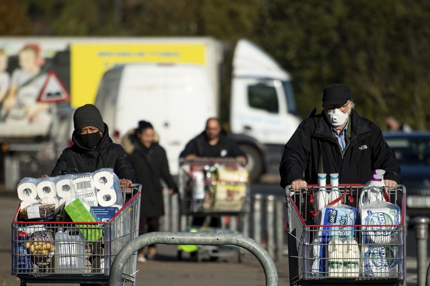 Shoppers leave a Costco store, ahead of a second lockdown, in Birmingham, England, Monday, Nov. 2 2020. Prime Minister Boris Johnson is facing opposition from his own party as he prepares to ask Briti ...