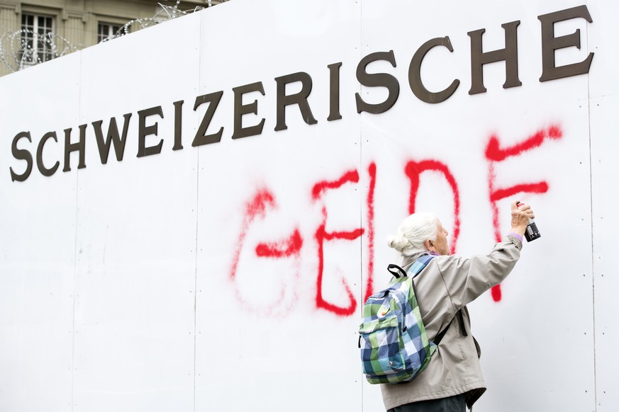 Die 86-jaehrige Louise Schneider, Friedensaktivistin, besprayt die SNB am Bundesplatz mit den Worten &quot;Geld fuer Waffen toetet&quot;, am Dienstag, 11. April 2017 in Bern. Am 11. April wird die Kri ...
