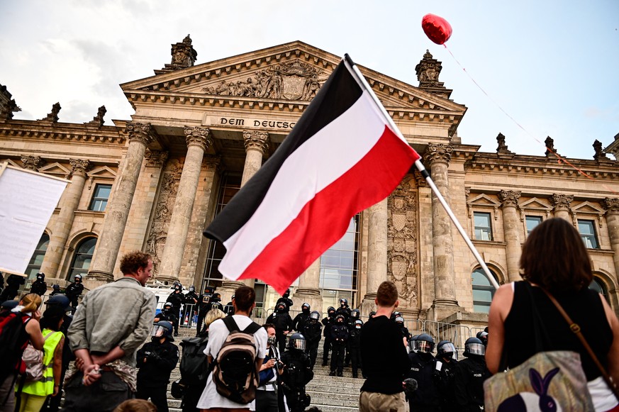 29.08.2020, Berlin: Teilnehmer einer Kundgebung gegen die Corona-Massnahmen stehen vor dem Reichstag, ein Teilnehmer haelt eine Reichsflagge. (KEYSTONE/DPA/Fabian Sommer)