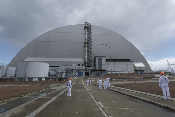 KEYPIX - epa12911038 Visitors walk next to the protective shelter over the remains of the nuclear reactor Unit 4 at Chernobyl nuclear power plant, in Chernobyl, Ukraine, 23 April 2026 (issued 24 April ...