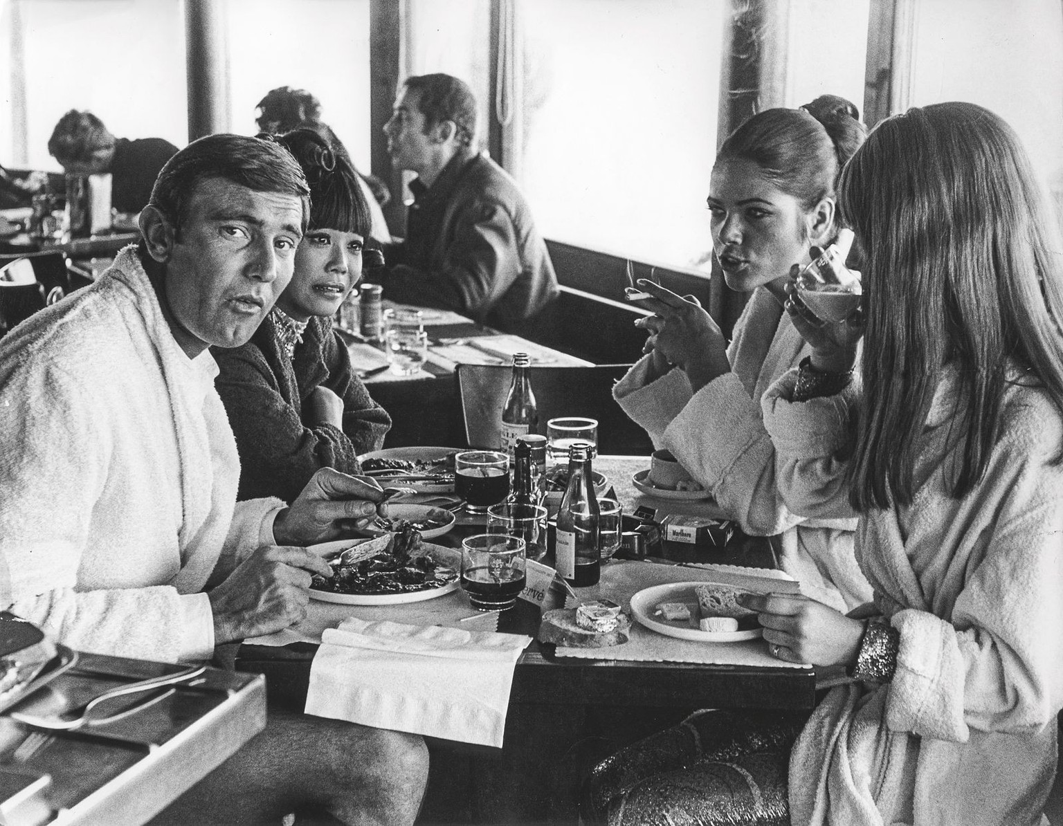 One floor below the Alpine Room, a canteen with a large kitchen is set up, capable of serving up to 120 people. The catering is handled by the kitchen of the Hotel Alpenruh.
Lazenby and the girls wear ...