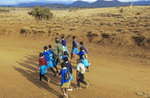 epa09388727 Lewa Wildlife Conservancy (LWC) ranger Rajimen Lesakut (L), escorts primary school children from nearby school as he assists them to walk across the wildlife conservancy as they went home  ...