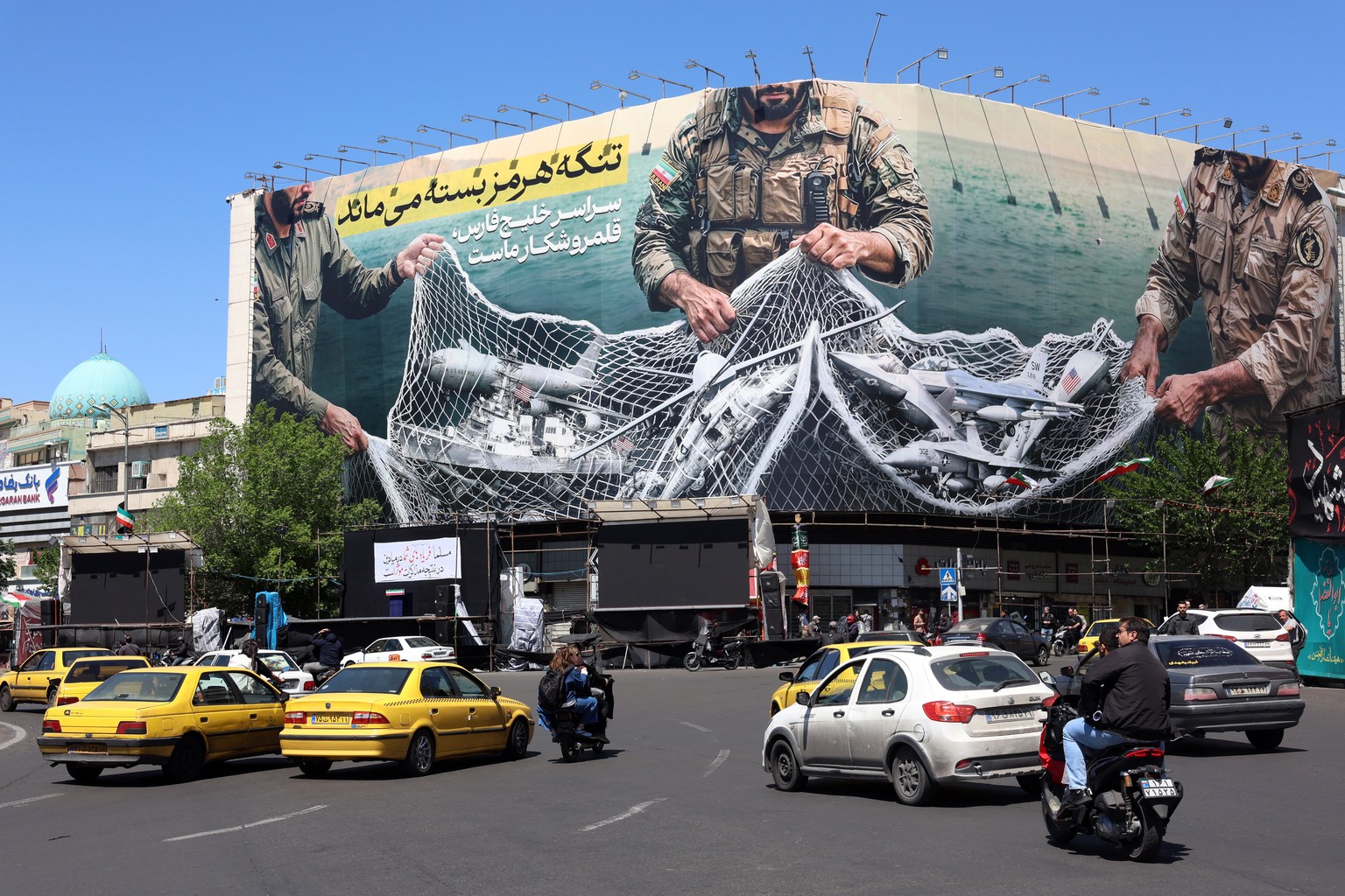 epaselect epa12906371 Iranians drive past a huge billboard carrying a sentence reading in Persian The strait of Hormuz remains closed at the Enghelab square in Tehran, Iran, 22 April 2026. US Presid ...