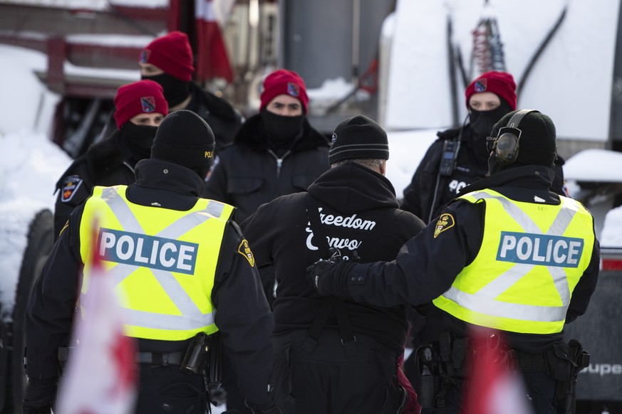 A trucker is led away by police after leaving his truck as police aim to end an ongoing protest against COVID-19 measures that has grown into a broader anti-government protest, Friday, Feb. 18, 2022,  ...