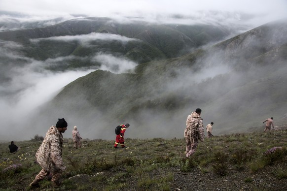 In this photo provided by Moj News Agency, rescue team members search for the wreckage of the helicopter carrying Iranian President Ebrahim Raisi after it crashed in Varzaghan in northwestern Iran, Mo ...