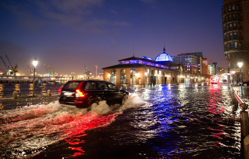 Ein Auto faehrt am 04.01.2017 in Hamburg waehrend einer Sturmflut ueber den ueberfluteten Fischmarkt vor der Fischauktionshalle. Das Sturmtief «Axel» beschert dem Norden Sturm und Hochwasser an den Ku ...