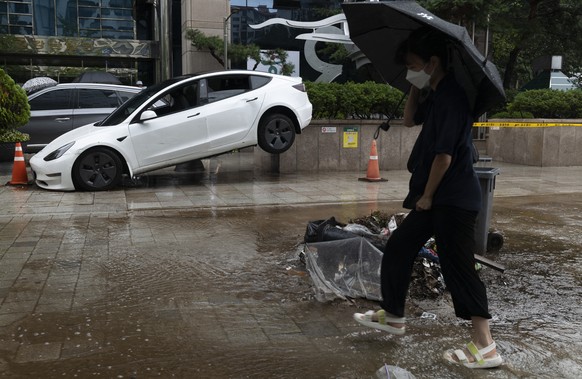 epa10112104 A woman walks next a damaged vehicle on a road amid heavy rainfall of over 100 millimeters per hour, the heaviest in 80 years, in Seoul, South Korea, 09 August 2022. The record downpours b ...