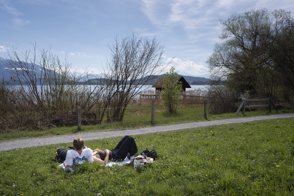 Junge Menschen liegen im Gras am Seeufer des Zugersees auf der Lorzenebene, zwischen Cham und der Stadt Zug, fotografiert am Montag, 6. April 2026 in Zug. Die Stiftung Landschaftsschutz Schweiz SL zei ...