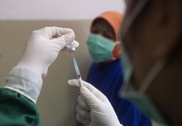 A nurse prepares to give a shot of the COVID-19 vaccine to a colleague at a hospital in Medan, North Sumatra, Indonesia, Monday, Jan. 25, 2021. The world's fourth most populous country has started giving COVID-19 vaccine to health workers this month as its first stage of a plan to vaccinate two-thirds of its population of about 270 million people. (AP Photo/Binsar Bakkara)
