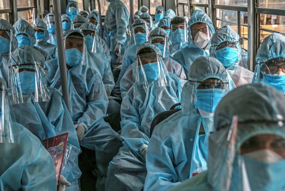 epaselect epa08490339 Indian healthcare workers and volunteers of Rashtriya Swayamsevak Sangh (RSS) wearing personal protective equipment (PPE) arrive to conduct medical check-up on residents at Ramab ...