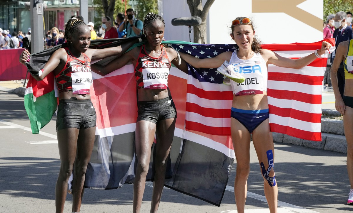 epa09402210 (L-R) Peres Jepchirchir of Kenya (gold), Brigid Kosgei of Kenya (silver) and Molly Seidel of the US (bronze) pose together after crossing the finish line during the Women's Marathon d ...
