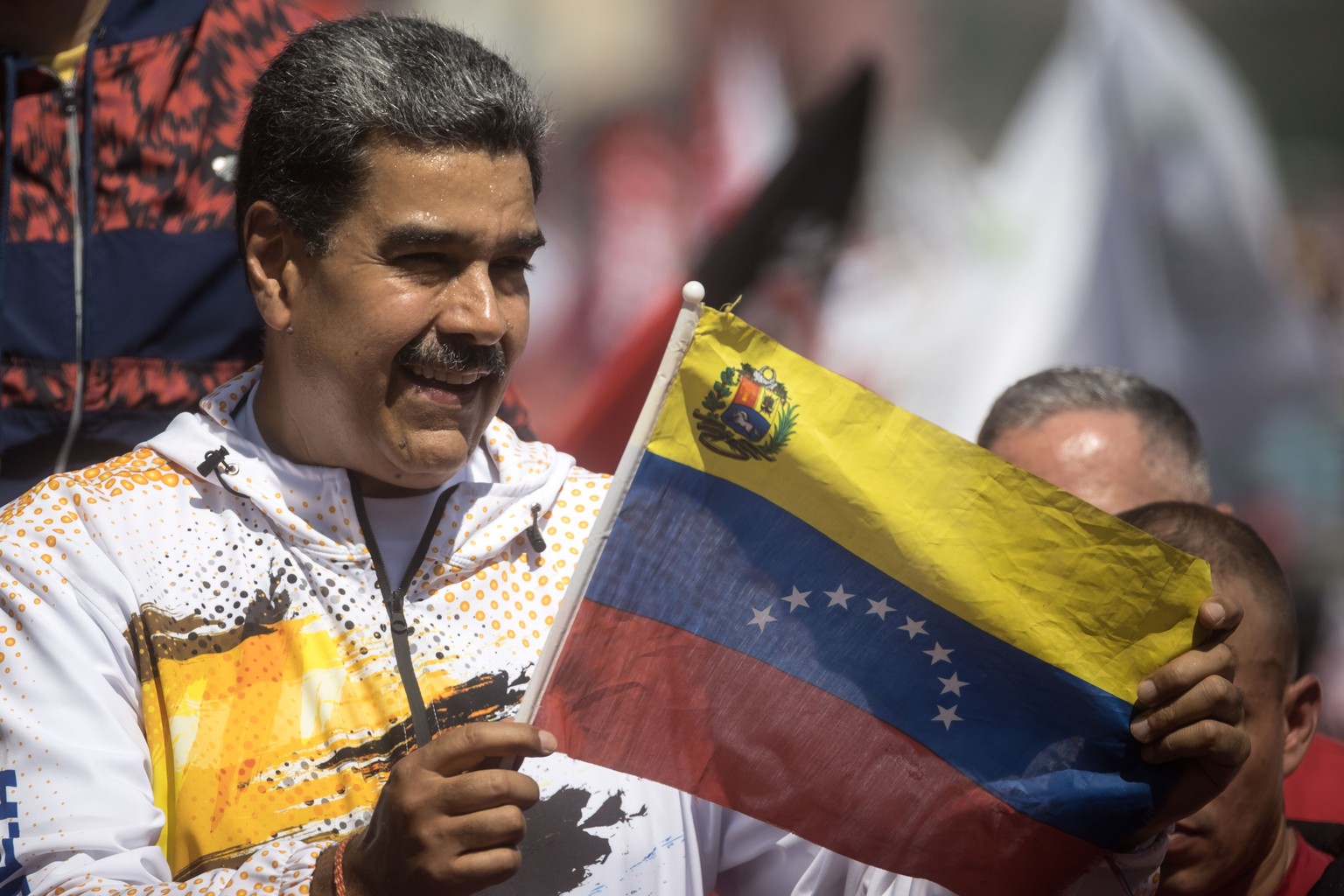 epa11243658 The president of Venezuela, Nicolas Maduro, holds a Venezuelan flag during a demonstration in support of his candidacy for a third term, outside the headquarters of the National Electoral  ...