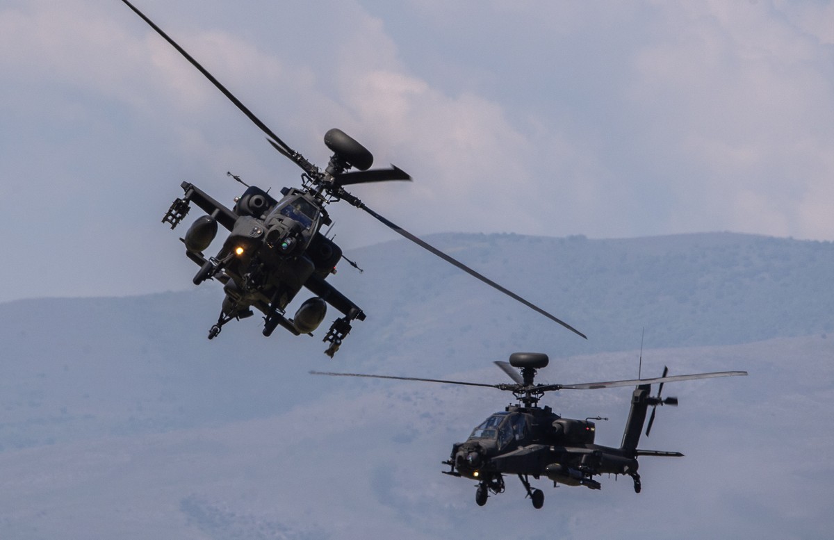 epa09942201 NATO forces' U.S. AH-64 Apache helicopters fly by during the NATO exercise 'Swift Respone 22' at the Krivolak Army Training Area, near Negotino, Republic of North Macedonia, ...