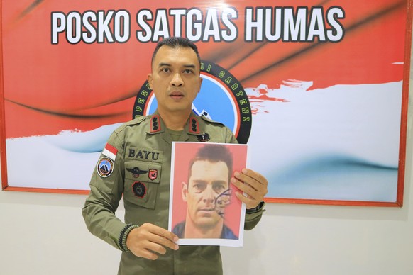 In these image released by Indonesian Police, Bayu Suseno, spokesperson for the Cartenz 2024 Peace Task Force, holds portrait of Glen Malcolm Conning, a pilot for Indonesian aviation company PT Intan  ...