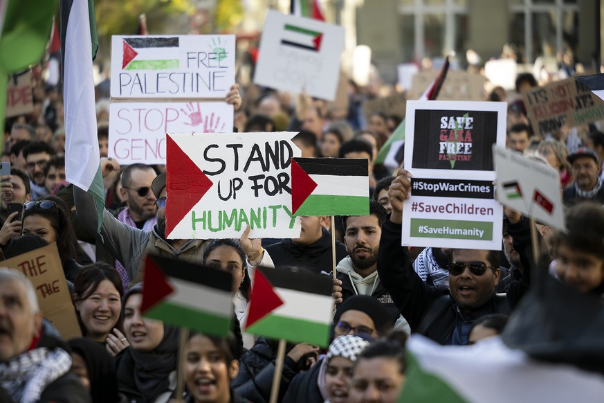 epa10944935 Protesters hold Palestinian flags and placards, during an authorized rally in solidarity with Palestine, at the Federal square, in Bern, Scwitzerland 28 October 2023. Thousands of Israelis ...