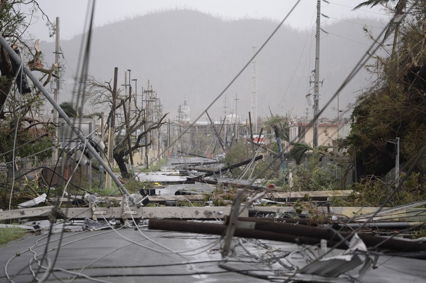 FILE - In this Sept. 20, 2017 file photo, electricity poles and lines lie toppled on the road after Hurricane Maria hit the eastern region of the island, in Humacao, Puerto Rico. Ten months after Hurr ...