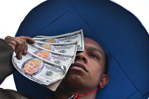 epa12527984 A person poses with US Dollars depicting US President Trump&#039;s likeness during the Global Climate March in Belem, Brazil, 15 November 2025, calling on governments to protect forests, u ...
