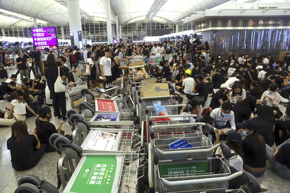 Protesters use luggage trolleys to block the walkway to the departure gates during a demonstration at the Airport in Hong Kong, Tuesday, Aug. 13, 2019. Protesters severely crippled operations at Hong  ...