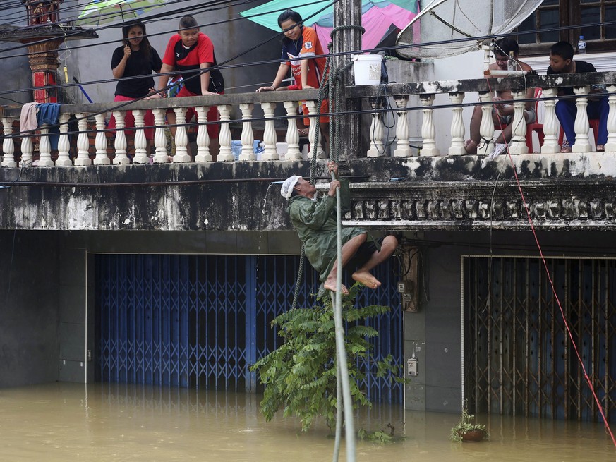 epa05700804 A Thai villager climbs on a sling to evacuate from a flood submerged house in Nakhon Si Thammarat province, southern Thailand, 06 January 2017. Since 01 January 2017 heavy rains have cause ...