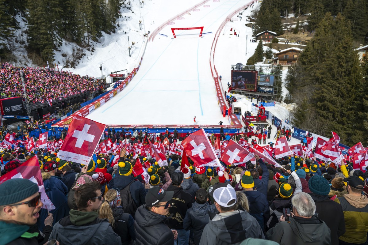 Spectators cheer with Swiss flags in the finish area during the men's Downhill race at the Alpine Skiing FIS Ski World Cup, in Crans-Montana, Switzerland, Saturday, February 22, 2025. (KEYSTONE/A ...